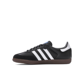 Youth black low-top sneakers with white stripes and gum outsole, side profile.