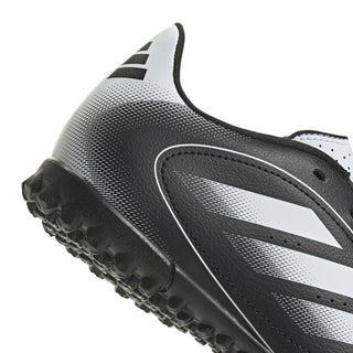 Close-up of youth soccer cleat side, black upper with white stripe and studded sole.