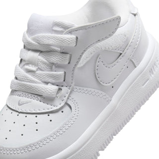 Toddler white low-top sneaker close-up with swoosh, laces, and textured midsole