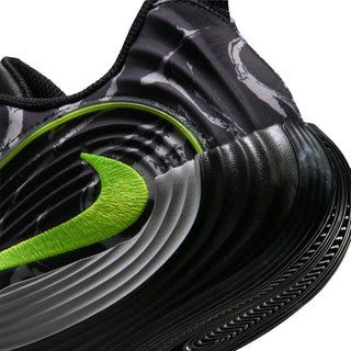 Close-up of black mens running shoe side with volt green logo and ridged midsole
