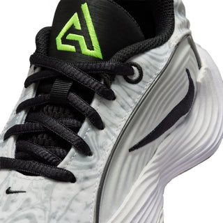 Kids sneaker close-up: black laces, neon green emblem on tongue, textured gray upper