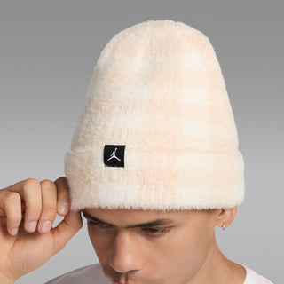 Cream plush beanie with black square logo patch, worn on head