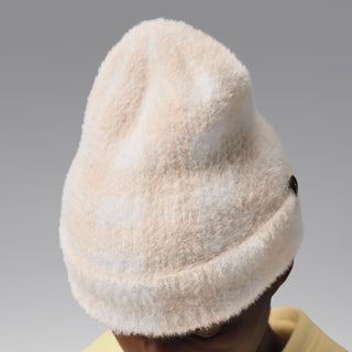 Cream plush beanie with black logo patch, back/side view