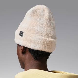 Cream plush beanie with black logo patch, side-back view