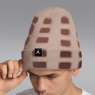 Fuzzy beanie worn on head with brown-and-cream geometric blocks and black logo patch