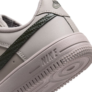 Kids sneaker close-up: light grey upper with dark green stripe and textured midsole