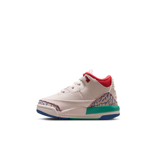 Toddler low-top sneaker side view in cream with red tongue and green-blue midsole
