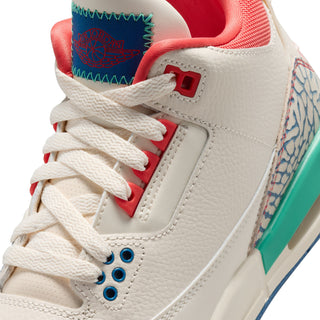 Youth sneaker close-up of laces and tongue with red accents, blue eyelets, and teal trim