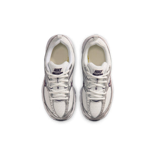 Pair of youth white sneakers with lace-up front and NIKE logo on tongue