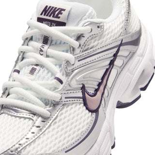Close-up of youth white sneaker with lace-up front, purple accents, and NIKE logo