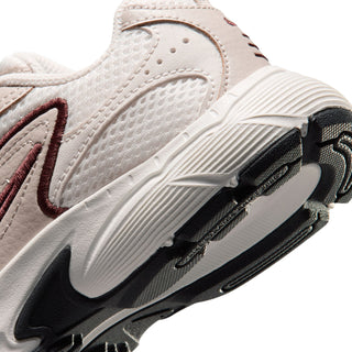 Close-up side view of kids light cream running shoe with black swoosh and sole