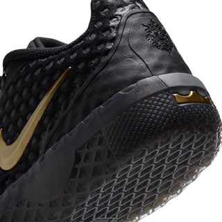 Close-up of youth black sneaker side with metallic gold accents and rubber outsole tread