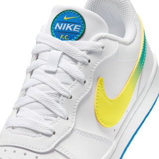 Youth low-top sneakers lace-up close-up, white with yellow swoosh and blue F.C. patch
