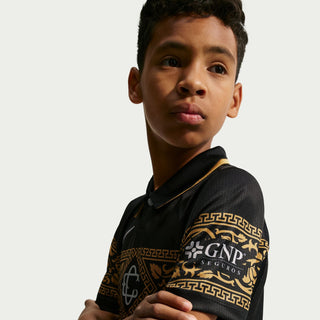 Youth black soccer jersey sleeve with gold patterned trim and crest detail
