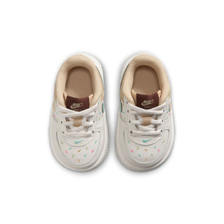 Toddler white Nike sneakers with teal swoosh and multicolor speckles, lace-up