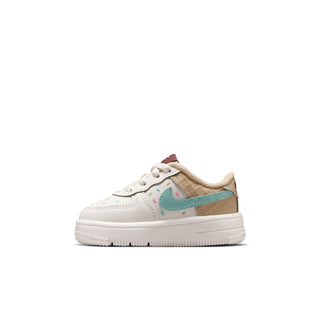 Toddler white Nike sneakers, side view, teal swoosh with multicolor speckles