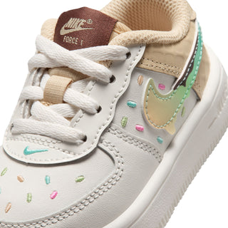 Toddler Nike sneakers close-up, white leather with teal swoosh and colorful sprinkles