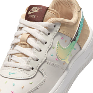 Kids' sneaker close-up with tan tongue, white laces, teal swoosh, and speckle dots