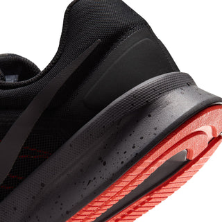 Men's black running shoe close-up of outsole and midfoot with orange-red tread