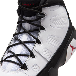 Kids high-top sneaker upper close-up, black laces, white panels, red tongue logo.