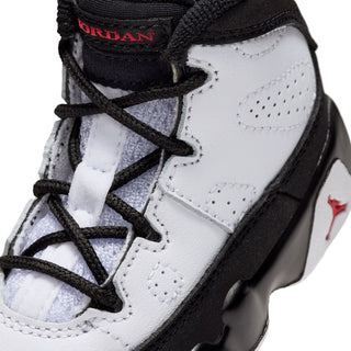Toddler sneaker detail, white upper with black laces, 'JORDAN' tag and red Jumpman.