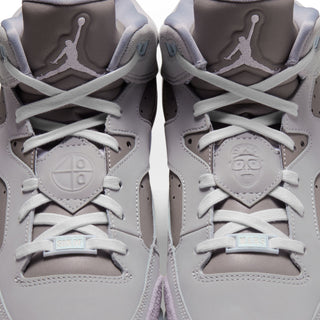 Men's sneaker front detail: light gray uppers, white laces, embossed face patch.