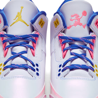 White youth sneakers with blue laces, pink accents, and Jumpman logos