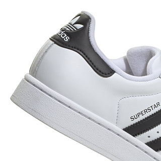 Close-up of women's white and black sneaker with SUPSERSTAR side text and white midsole