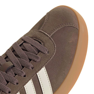 Women’s suede sneaker close-up at laces and toe, taupe color with stitched seams