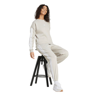 Womens light beige loose track pants with white 3-Stripes, sitting model view