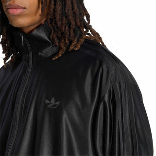 Men's black track jacket shoulder and chest close-up, trefoil-style logo and zip