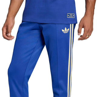 Men's blue track pants with vertical gold side stripes and adidas trefoil patch