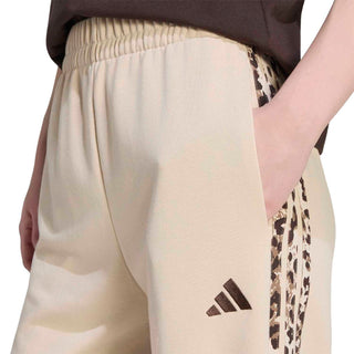 Womens beige pants with elastic waistband and small adidas logo near side stripe