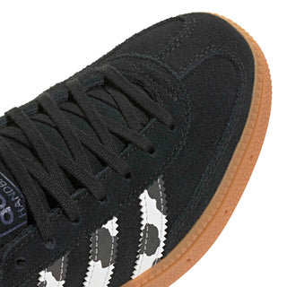 Close-up of youth black suede sneaker with white serrated stripes