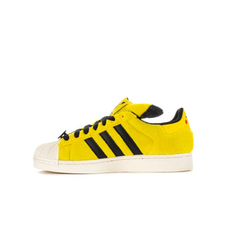 Youth yellow low-top sneaker with black stripes, black lace-up eyelets, and white sole