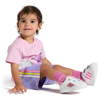 Toddler wearing white sneakers with Care Bears rainbow patch and pink details