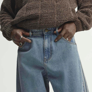 Close-up of mens light blue denim pants waistband with front pockets and metal button