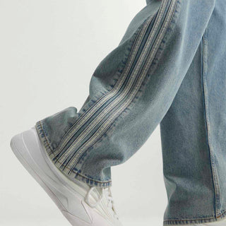 Detail of mens light blue denim pants hem and side stripe stitching