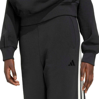 Women's black track pants with off-white side stripe and small logo at hip