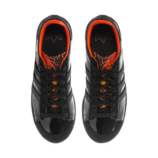 Black low-top sneakers with orange-trimmed collar and black lace-up front