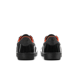 Black low-top sneakers, rear view, with orange inner lining and flat rubber sole