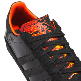 Close-up of black sneaker upper with orange graphic toe panel and black lace-up