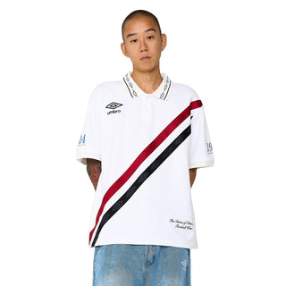 White Umbro polo shirt on model, diagonal red-and-black stripe and small chest crest