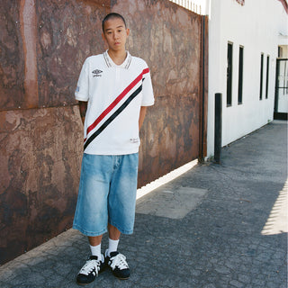 White polo shirt with diagonal red-and-black stripe and small chest Umbro logo