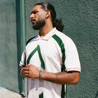 Men's off-white collared jersey with green shoulder panels and front graphic detail