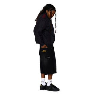Men's black denim carpenter shorts, side view with Umbro logo patch