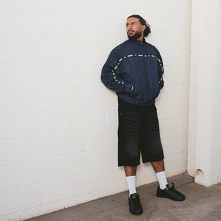 Men's black denim carpenter shorts on model, knee-length with side pocket tabs