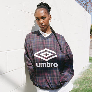Plaid V-neck windbreaker with Umbro logo, dark check over white pants.