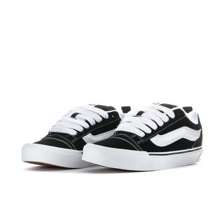 Men's black-and-white low-top sneakers, side view with white laces and stitched panels