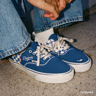 Men's low-top Vans sneakers being worn, blue uppers with Dodgers script and checker trim